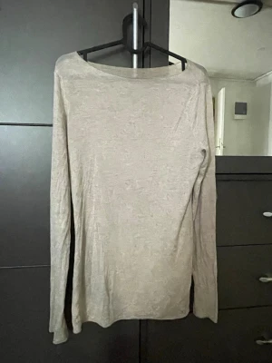 intinmissmi  uångärmad tröja - ( sitter bra på s lite lång bara) En enkel och stilren beige långärmad tröja med rund hals. Tröjan har en rak passform och är tillverkad i ett tunt, mjukt material som känns skönt mot huden. Perfekt att matcha med jeans eller kjol för en clean look.