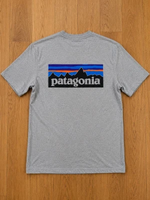 Patagonia t-shirt - Snygg grå t-shirt från Patagonia med stor färgglad logga och bergmotiv på ryggen samt liten logga på bröstet. Klassisk passform och rund halsringning. Tillverkad i mjuk bomull som känns skön mot huden.