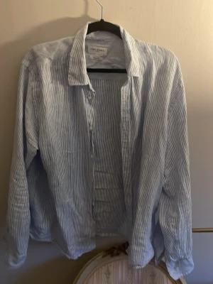 Randig linne  skjorta från John Henric - Snygg blå- och vitrandig skjorta från John Henric i casual fit. Skjortan har klassisk krage, knäppning framtill och långa ärmar. Perfekt för en chill och stilren look.