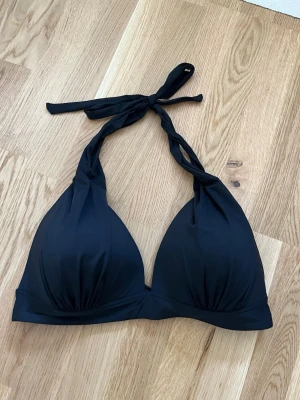 Svart bikinitopp från twilfit  - Ny bikinitopp som endast är provad💕 snygg, stilren svart bikinitopp med vadderade kupor. Knyts i nacken och i ryggen och ger en fin passform🥰 Prislappen finns kvar, men avklippt från plagget! Hör gärna av dig vid frågor💕Säljer då den inte satt som jag ville🥰
