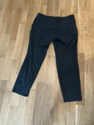 Mörkgrå kostymbyxor från Only & Sons - Snygga mörkgrå kostymbyxor från Only & Sons i modellen ONSMARK SLIM. Byxorna har två bakfickor med knapp och är tillverkade i ett mjukt, lätt material som passar perfekt till en dressad look. Slim fit och klassisk design.