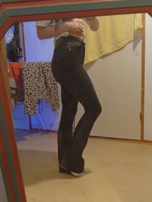 Svarta bootcut jeans med hög midja - Snygga svarta jeans med bootcut-modell och hög midja. Jeansen har klassisk femficksdesign och sitter tight upptill med utsvängda ben.Har lite hål ner till foten. Perfekta för dig som gillar en tidlös och trendig look.