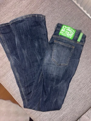 Mörkblåa Cheap Monday jeans - Säljer ett par mörkblå jeans från Cheap Monday med klassisk femficksdesign och snygga slitningar. Jeansen har en grön logga på bakfickan och är tillverkade i bomullsdenim med lite stretch. Perfekta för dig som gillar en avslappnad och trendig look.