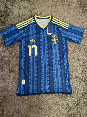Sverige fotbollströja  - Blå Sverige fotbollströja från Adidas med Gyökeres och nummer 17 på ryggen. Matchtröjan är Sveriges officiella borta tröja inför VM. Tröjan är ”authentic” vilket betyder att den är i samma material som spelarnas. Tröjan är aldrig använd, eftersom den var för liten och inte gick att lämna tillbaka. Tröjan har prislapp och förpackning kvar.