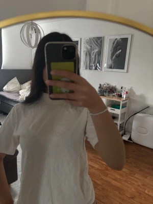 Vit basic t-shirt med hög hals - Enkel vit t-shirt med hög hals och korta ärmar. Perfekt att styla till jeans eller kjol för en clean look. T-shirten har en rak passform och är tillverkad i mjukt bomullsmaterial.