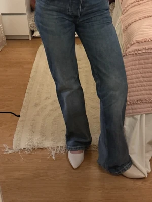 Blå raka jeans med låg midja  - Säljer ett par klassiska blå jeans från Zara,  med rak passform och låg midja. Jeansen har fem fickor och stängs med knappar. 
