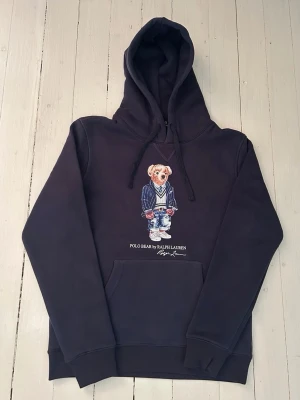 Ralph Lauren polo bear hoodie storlek S - Hej! Säljer denna riktigt schyssta polo bear hoodie från Ralph Lauren. Den är i storlek M men sitter en storlek litet och passar därför som en S. Den är endast använd någon enstaka gång och är därmed i ett nyskick. Om den ser fläckig/solblekt ut är det endast pga dåligt fotoljus. Original lappar och påse finns kvar och medföljer naturligtvis vid köp. Jag fraktar alltid snabbt! Mvh