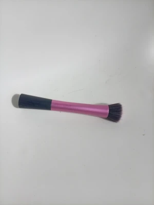 Rosa stippling brush från Real Techniques - En sminkborste med svart handtag och rosa metallfärgat skaft från Real Techniques. Borsten är en stippling brush med täta, tvåfärgade syntetiska strån som ger en jämn applicering av foundation eller rouge.