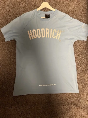Ljusblå HOODRICH t-shirt med tryck - Snygg ljusblå t-shirt från HOODRICH med stort vitt tryck framtill och inspirerande text på ryggen. Klassisk passform med korta ärmar och rund hals. Tillverkad i mjuk bomull som känns skön mot huden.