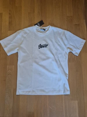 Vit t-shirt från Pull&Bear - Vit t-shirt från Pull&Bear med svart tryck framtill.Klassisk rund halsringning och korta ärmar. Tillverkad i mjuk bomull för en skön känsla. Perfekt för en avslappnad och stilren look. Helt ny, oanvänd.