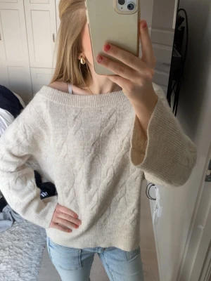 Stickad tröja - Mysig offwhite kabelstickad tröja med bred ribbad kant och avslappnad passform. Tröjan har en något vid halsringning och långa ärmar. 💕