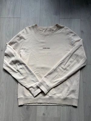 Archive Logo Sweater - Mörkvit tröja från Saint Laurent. Sällsynt modell med slitningar i muddar och fade på logotyp från fabrik. Saknar necktag annars riktigt fint skick, möjligtvis någon ytterst liten missfärgning på något ställe. Storlek L, kan även passa M. Fråga om mått vid intresse.