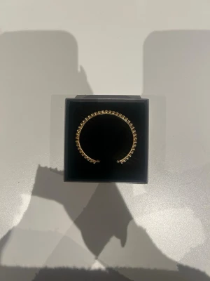 Caroline Svedbom armband - Snyggt och stilrent armband i guldfärg med små kristaller längs hela bandet. Armbandet är stelt och öppet i modellen vilket gör det enkelt att ta på och av. Perfekt accessoar för att lyfta vilken outfit som helst. Helt oanvänd, från Caroline Svedbom💓