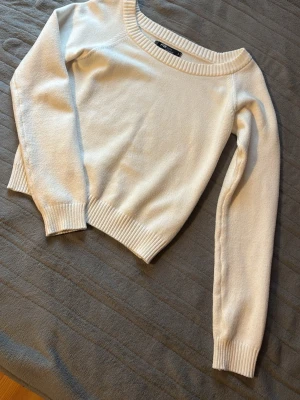 Vit stickad tröja från New yorker - Snygg vit stickad tröja med rund halsringning och ribbade muddar vid ärmslut och nederkant. Tröjan har en klassisk, enkel design och är perfekt att matcha med jeans eller kjol. Mjuk och skön kvalitet. Är i storlek S 