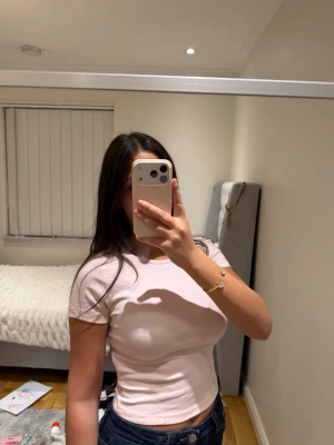 Ljusrosa tight t-shirt - Säljer en ljusrosa, tight t-shirt med korta ärmar och rund halsringning. T-shirten är enkel och stilren, perfekt att matcha med jeans eller kjol. Materialet känns mjukt och stretchigt, vilket gör den bekväm att bära hela dagen.