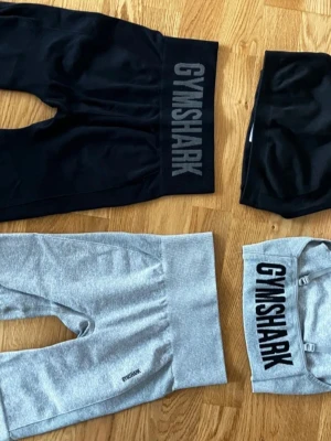 Gymshark träningsset svart & grå - Två träningsset från Gymshark, ett i svart och ett i ljusgrått. Båda seten består av sport-bh och bikershorts med hög midja. Perfekta för gymmet. Materialet är stretchigt och följsamt. 300kr per set