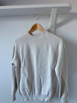 Vit ribbstickad tröja - En stilren vit stickad tröja med ribbad struktur. Perfekt för lager-på-lager och enkel att matcha med olika outfits.