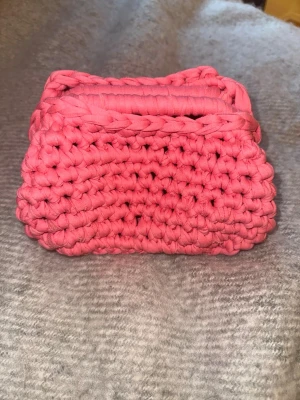 Rosa clutch bag - Superfin handgjord kuvertväska i en härlig rosa färg. Väskan är stickad med grovt garn och har en mjuk, chunky känsla. Perfekt att bära till dina favoritoutfits för en färgklick och unik stil. Storlek: ca 20x16x10 cm                           Handgjord av mig med material från panduro 