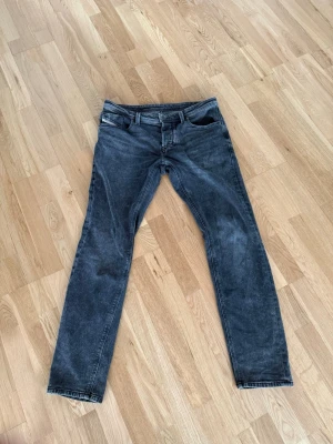 Grå jeans från Diesel - Snygga grå jeans från Diesel med klassisk femficksmodell och tydlig tvättad look. Jeansen har bälteshällor och detaljerade sömmar. Märkeslapp med Diesel-logga på insidan. Perfekta för dig som gillar street och casual stil. Dessa sitter mer slim, köpta på carlings