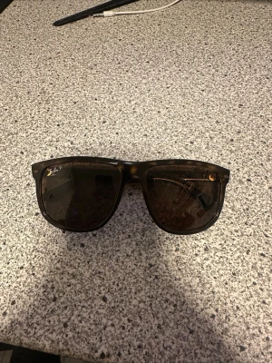 Rayban boyfriends - Snygga svarta solglasögon med rektangulär form och stilren design. Bågarna är gjorda i syntetmaterial och ger en modern look. Perfekta för att lyfta din outfit med en cool touch. Repor på ena glaset. Hör av er vid frågor