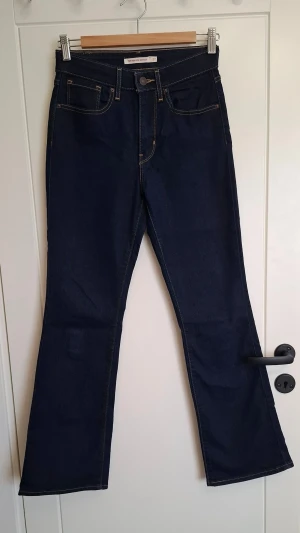 Mörkblå bootcut jeans från Levi's - Säljer ett par vintage mörkblåa bootcut jeans från Levi's med klassiska fem fickor och kontrastsömmar. Jeansen har hög midja och är tillverkade i ett kraftigt denimtyg. Perfekta för dig som gillar en tidlös och snygg look.