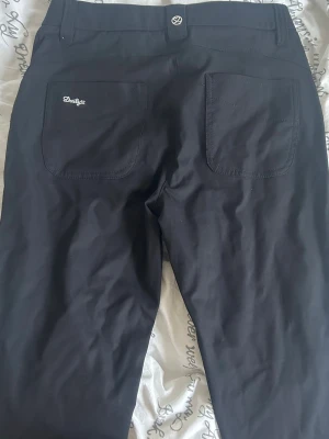 Svarta jeans från Dailys - Snygga svarta jeans från Dailys med raka ben och två bakfickor. Jeansen har broderad logga på ena bakfickan och klassiska bälteshällor. Materialet känns mjukt och följsamt, perfekt för en clean och stilren look. Aldrig använda!