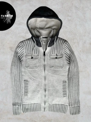 Stickad fodrad cardigan jacka - Stickad cardigan jacka i ljusgrå med mjukt vitt fleecefoder och quiltad mörkblå stoppning på insidan för extra värme. Fast huva, bröstficka med knapp och sidoficka. Skicket är nästintill ny utan några defekter och knappt använd. Storlek S men kan även passa M. Hör av dig för mått!                                                                             ~ Nypris okänt liknande säljs för 800-1200kr | Vårt pris 999 kr. Alla följare får rabatt, så följ!