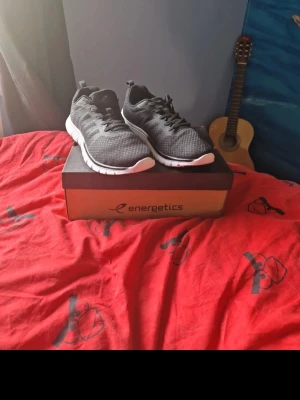 Svarta Energetics sneakers mesh - Snygga svarta sneakers från Energetics med ovandel i mesh för bra andningsförmåga. Skorna har vita sulor och svarta skosnören. Perfekta för dig som gillar sportig stil och vill ha bekväma skor till vardagen.