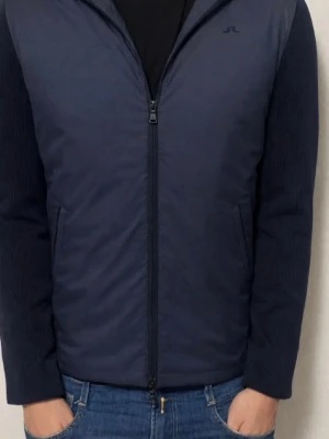 Marinblå cardiganjacka/vindjacka/hybridjacka från J.Lindeberg - Snygg marinblå cardiganjacka från J.Lindeberg med dragkedja framtill och huva. Jackan har stickade ärmar och rygg i mjukt material samt vadderad framsida och huva för extra värme. Perfekt för lager på lager och en stilren look. (Nypris 3600)(Perfekt skick)