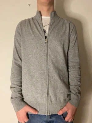 Ljusgrå ziptröja med hög krage - Säljer en stilren ljusgrå ziptröja från Bruun & Stengade. Modellen på bilderna är 178cm och väger cirka 70kg. Hör gärna av er vid funderingar eller frågor! 