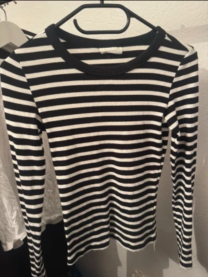 Randig långärmad topp Gina Tricot - Säljer en svartvit randig långärmad topp från Gina Tricot, basically basics-kollektionen. Toppen är ribbad och har en klassisk rund halsringning. Perfekt att styla med jeans eller kjol för en enkel och snygg look.