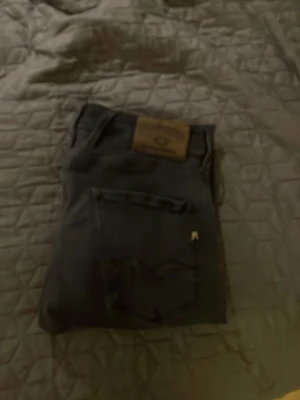 Svarta jeans från Replay - Säljer ett par svarta jeans från Lee med klassisk femficksdesign och rak passform. Jeansen har en brun läderpatch med Lee-loggan bak i midjan och är tillverkade i ett slitstarkt denimtyg. Perfekta för dig som gillar en tidlös och clean look. W30 L30