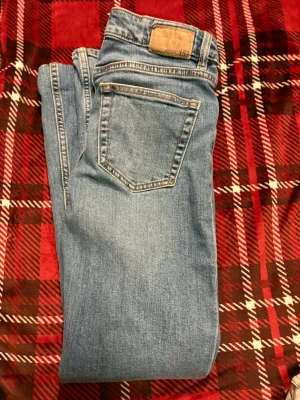 Blå jeans från 157, storlek XS - Säljer ett par klassiska blå jeans från 157 i storlek XS och short längd. Jeansen har en rak passform, fem fickor och tydliga kontrastsömmar. Perfekta till vardags och lätta att matcha med olika stilar.
