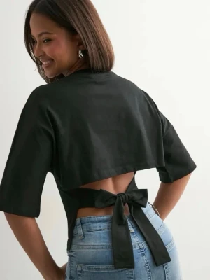 Svart topp med knyt i ryggen - Trendig svart topp med halvlånga ärmar och snygg knytning i ryggen. Toppen har en croppad passform och är perfekt för att skapa en cool look. Tillverkad i ett mjukt material som känns skönt mot huden.