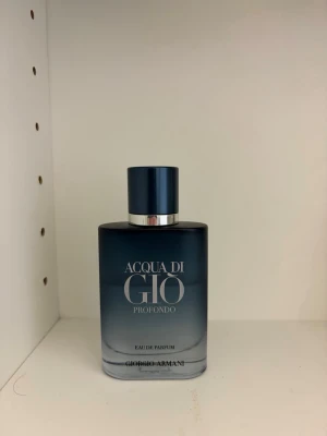 Acqua di Giò Profondo parfym - Acqua di Giò Profondo från Giorgio Armani är en elegant parfym i en stilren, matt mörkblå glasflaska med silverdetaljer. Flaskan har en fyrkantig form och ett matchande blått lock. Doften är en Eau de Parfum och flaskan utstrålar lyx och modernitet.