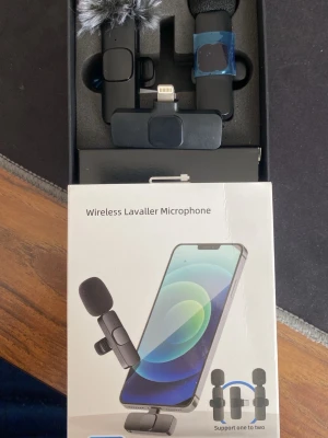 Trådlös mikrofon till iPhone - Säljer två trådlösa mikrofoner mottagare för iPhone , inklusive USB-laddkabel, puffskydd och vindskydd. Mikrofonerna är svarta och har Lightning-kontakt, perfekt för inspelning och streaming. Kommer i originalförpackning.