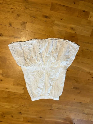 Vit kjol med broderade detaljer - Söt vit kjol i bomull med broderade hålmönster och resår i midjan. Kjolen har en luftig och volangig form som ger en romantisk känsla. Perfekt för varma dagar och enkel att matcha med olika toppar.