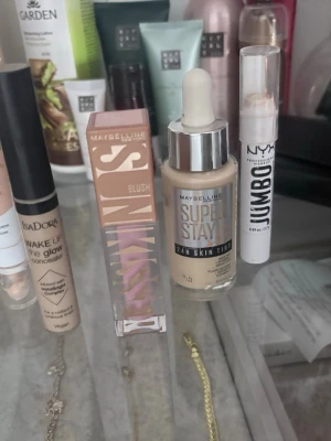 Maybelline Super Stay 24H Skin Tint - Maybelline Super Stay 24H Skin Tint foundation i en ljus beige nyans. Kommer i en glasflaska med pipett för enkel applicering. Ger en naturlig finish och är perfekt för dig som vill ha en lätt men täckande bas.