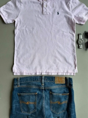 Ralph Lauren | Piké | - Säljer en klassisk rosa pikétröja från Polo Ralph Lauren för herr. Tröjan har en tidlös design med krage, knappslå och den ikoniska broderade Polo-logotypen på bröstet. Den passar perfekt både till vardags och för en mer välklädd stil. Tröjan är i mycket gott skick och har tagits väl om hand. Hör gärna av dig om du har frågor eller vill se fler bilder.