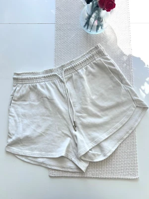 Vita mjukisshorts, storlek M - Säljer ett par vita/cremevita mjukisshorts från H&M i storlek M. True to size. Har en liten prick fram på höger sida, se bild 4.