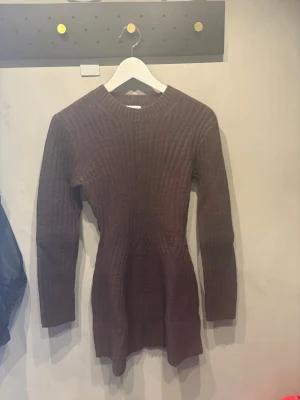 Brun ribbad stickad klänning H&M XS - Mysig brun stickad klänning från H&M i storlek XS. Klänningen har lång ärm, ribbad struktur och en kroppsnära passform som framhäver figuren. Perfekt för kyligare dagar och enkel att styla med boots eller sneakers.