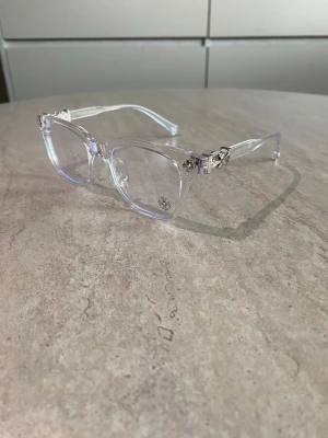 Chrome heart glasögon - Snygga solglasögon från Chrome heart med transparent båge och unika silverfärgad detaljer vid gångjärnen. Anti blue lights. Lätta och bekväma att bära hela dagen.