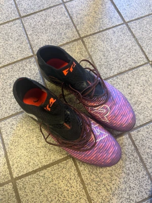 Puma Future rosa/lila fotbollsskor - Säljer ett par Puma Future fotbollsskor med snyggt rosa och lila mönster, svarta detaljer och högt skaft. Enbart testade en gång. Splitternya. 