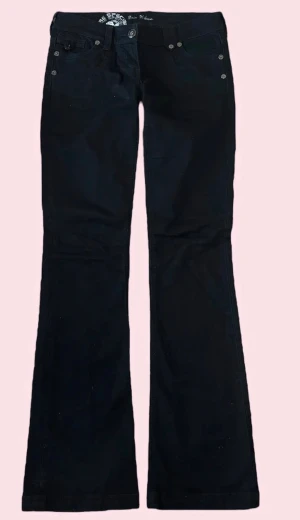 Svarta bootcut jeans lågmidjade - Snygga svarta bootcut jeans från The Specimen med dekorativa sömmar på bakfickorna och silverfärgade nitar. Jeansen har låg midja och klassisk femficksmodell. Perfekta för dig som gillar en retroinspirerad look med lite vidare ben. LÅG midja 