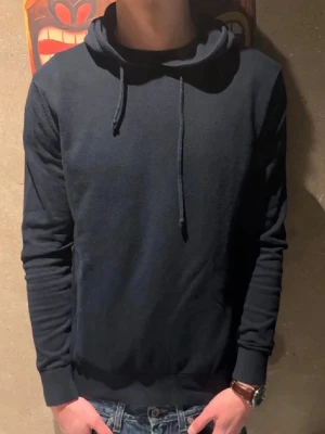 Mörkblå hoodie  - Snygg mörkblå hoodie med huva. Perfekt för dig som gillar en clean och avslappnad look. Tillverkad i mjukt bomull material som känns skönt mot huden. Modellen är 185cm