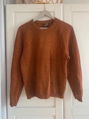 Rostbrun stickad tröja med rund hals - Säljer en snygg rostbrun stickad tröja med rund halsringning och långa ärmar. Tröjan har ribbade muddar vid ärmslut och nederkant. 100% ull.