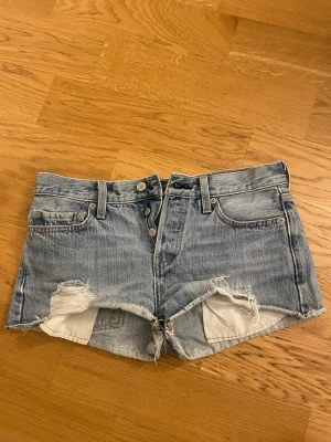 Levi's ljusblå jeansshorts med slitningar - Säljer ett par ljusblå jeansshorts från Levi's med råa kanter och slitna detaljer framtill. Passar xs/s