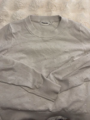 Ljusgrå stickad tröja Kappahl - Ljusgrå stickad tröja från Kappahl med diskreta små bollar i strukturen. Tröjan har rund halsringning, långa ärmar och ribbade muddar vid ärmslut och nederkant. Perfekt för dig som gillar enkel men ändå unik stil. Köpte den hära tröjan för ungefär 400 kr men jag säljer den nu för att den är lite för liten