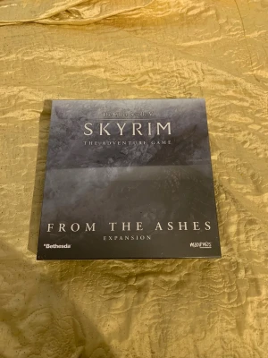 Skyrim From the Ashes Expansion - The Elder Scrolls V: Skyrim The Adventure Game - From the Ashes Expansion är en tilläggsbox till brädspelet Skyrim. Innehåller figurer, kort och spelmaterial i en svart och grå kartong med fantasytema. Perfekt för dig som vill utöka ditt Skyrim-brädspel. Ny pris: 939kr