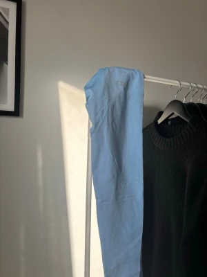 Ljusblå leggings från ICANIWILL - Snygga ljusblå leggings från ICANIWILL med diskret logga vid höften. Tillverkade i ett stretchigt och mjukt material som sitter skönt på kroppen. Perfekta för träning eller chill dagar. Tight passform och hög midja för en modern look. Använda fåtal gånger, som nya!